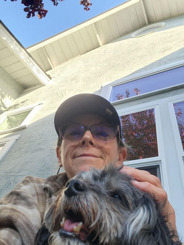 Taletha outside with a scruffy small dog resting against her