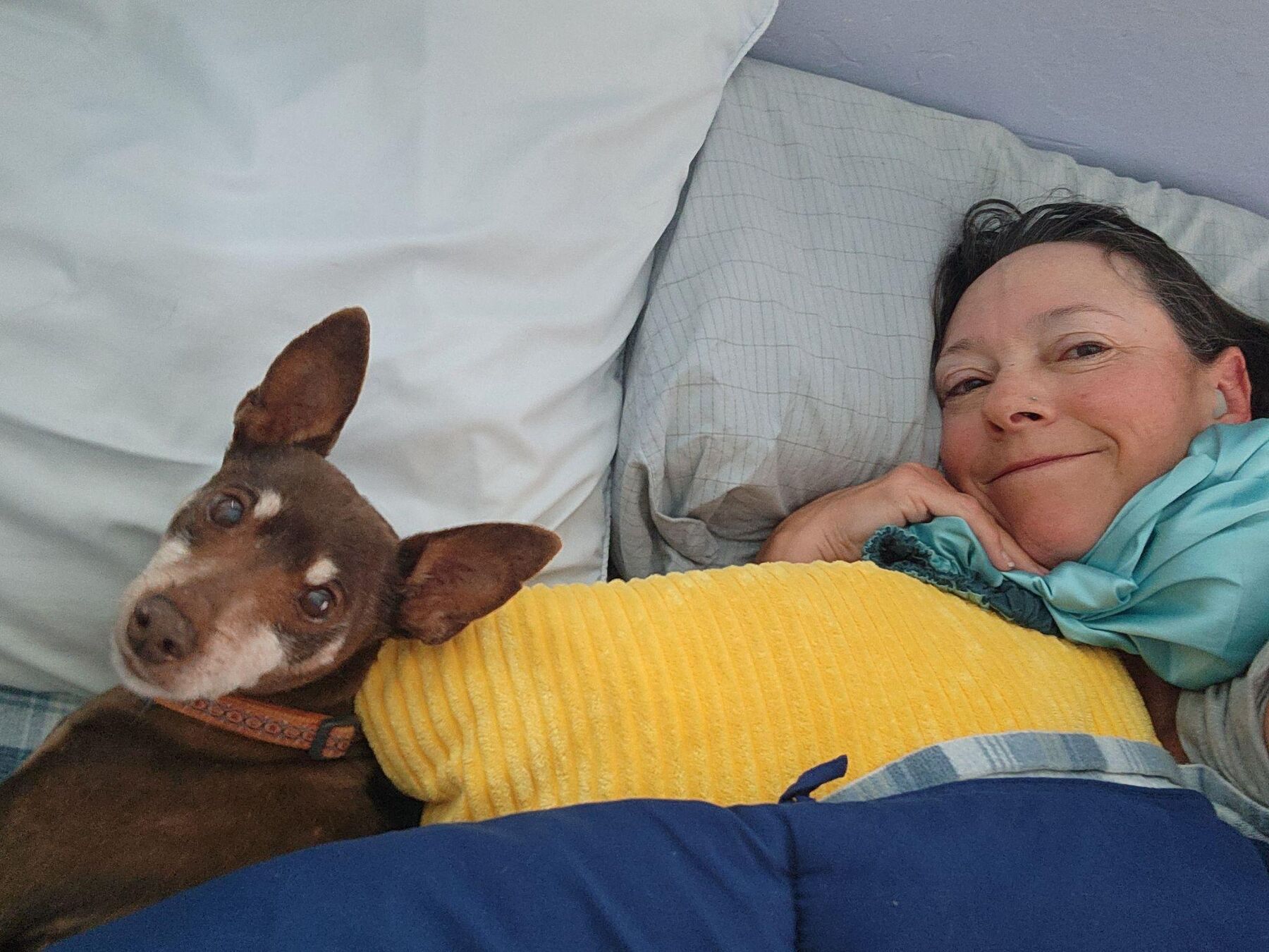 Taletha resting with a small dog curled against her